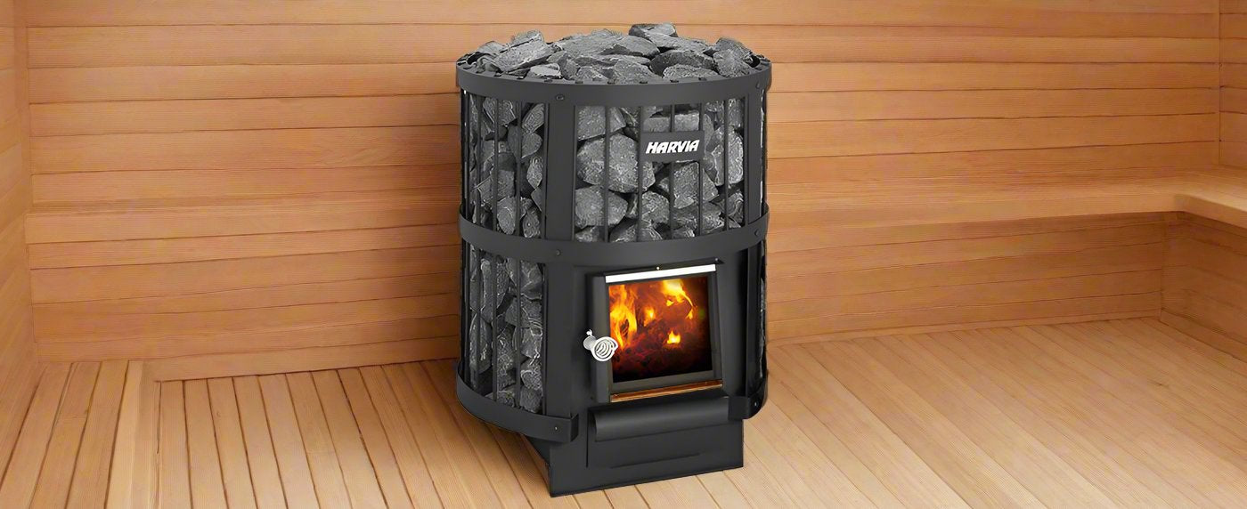 A Harvia wood-burning sauna heater filled with stones and containing a lit fire inside a wooden sauna room.