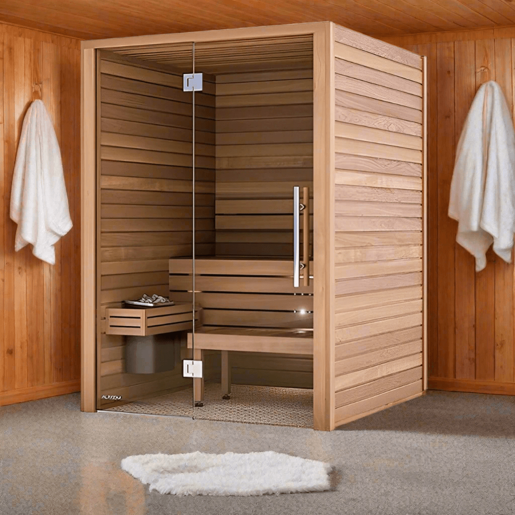 Auroom Cala Glass Thermo-Aspen indoor cabin sauna in a wood-panelled room with towels