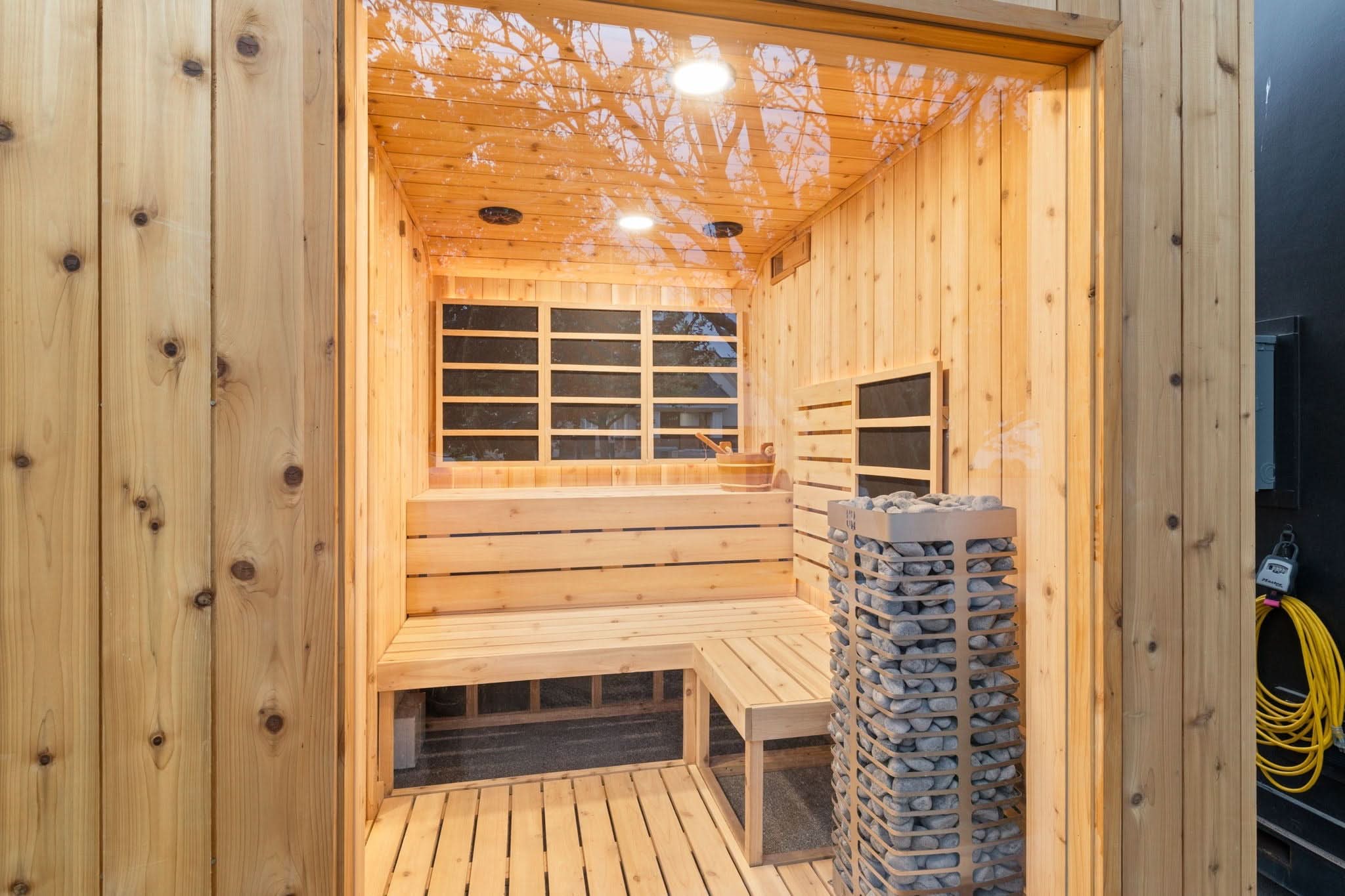 Sweaty Yeti 4-6 Person Outdoor Sauna & Cold Plunge Cabin in glass window with heater and wooden benches.