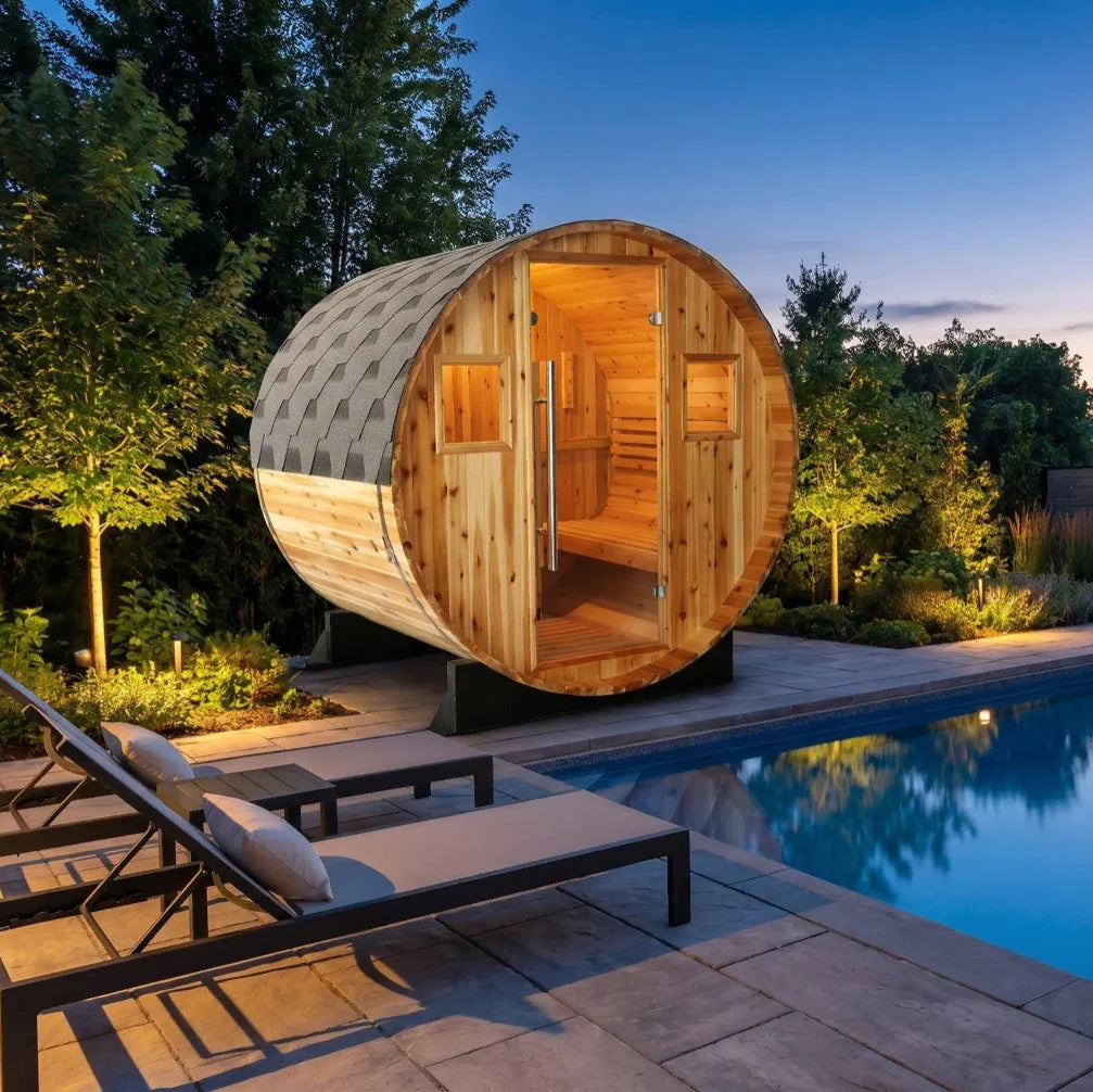 Solace barrel sauna with shingled roof beside a pool at twilight