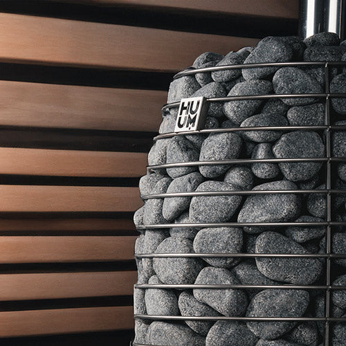 Close-up of the HIVE Flow stone cage with HUUM logo against wood slat walls