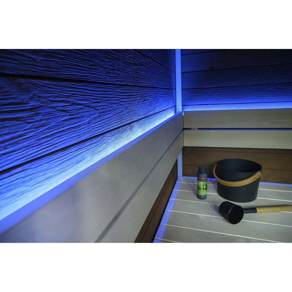Infrared sauna with blue LED lighting and a bucket and ladle on the floor.