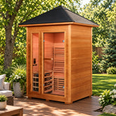 A single-story wooden infrared sauna with a black pyramid roof, glass doors, and visible wooden benches inside, shown on a plain white background.
