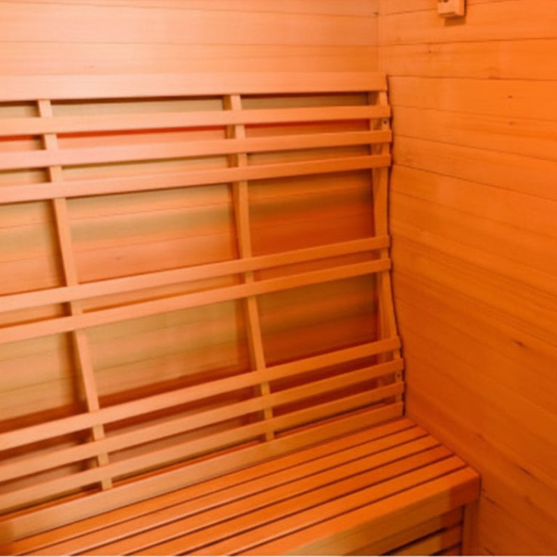 A wooden sauna interior with a slatted bench on the left and wood-paneled walls, shown in warm orange lighting.