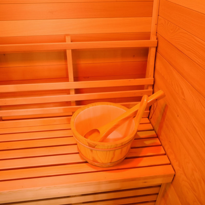 A light wood sauna bucket with a wooden scoop resting inside, placed on a wooden sauna bench.