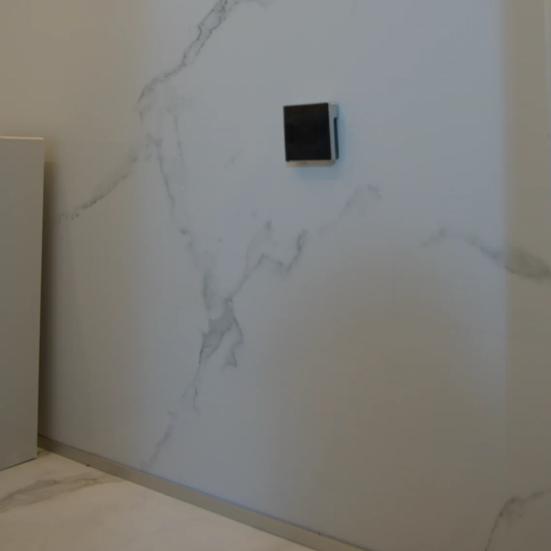 Modern wall-mounted speaker on a marble-textured wall