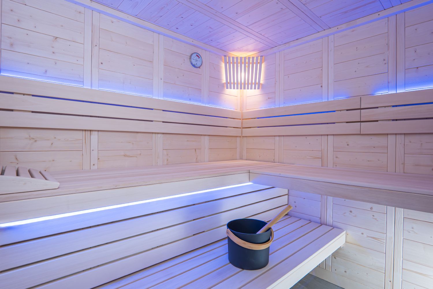 Wooden sauna interior with a bucket and ladle on a bench.