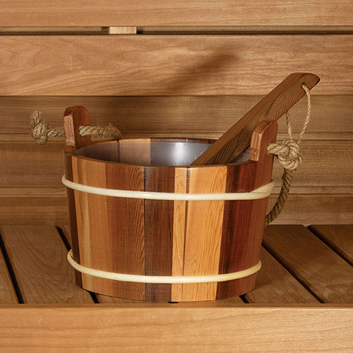 Wooden bucket with metal interior on a wooden surface with ladle in rope