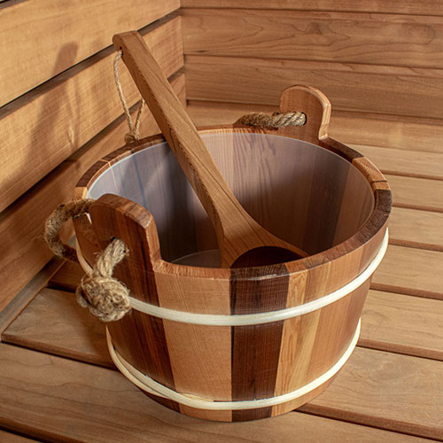Wooden bucket with a wooden spoon in rope on a wooden surface