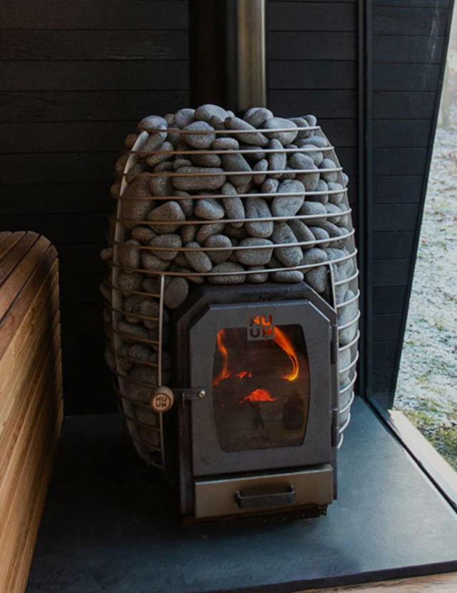 Sauna heater filled with stones inside a traditional sauna.