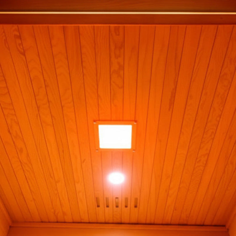 A view looking up inside a wooden sauna or room with warm orange ambient lighting, showing a slatted wooden ceiling with two lights and a rectangular opening at the top.