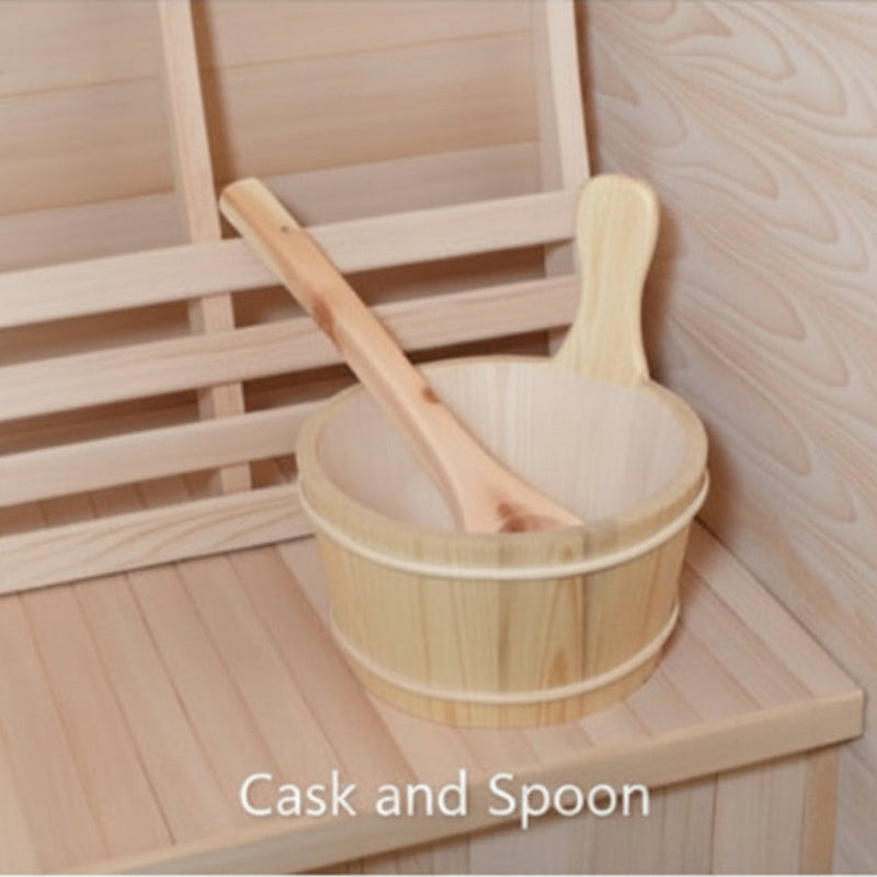 A light natural wood bath cask with a wooden spoon resting inside, placed on a wooden bench in a sauna-like setting. The text 'Cask and Spoon' appears near the bottom.