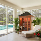SunrayWaverly A wooden indoor-outdoor sauna cabin with glass doors and a dark roof, placed beside a white lounge chair in a bright screened-in patio area with a pool and potted plants.