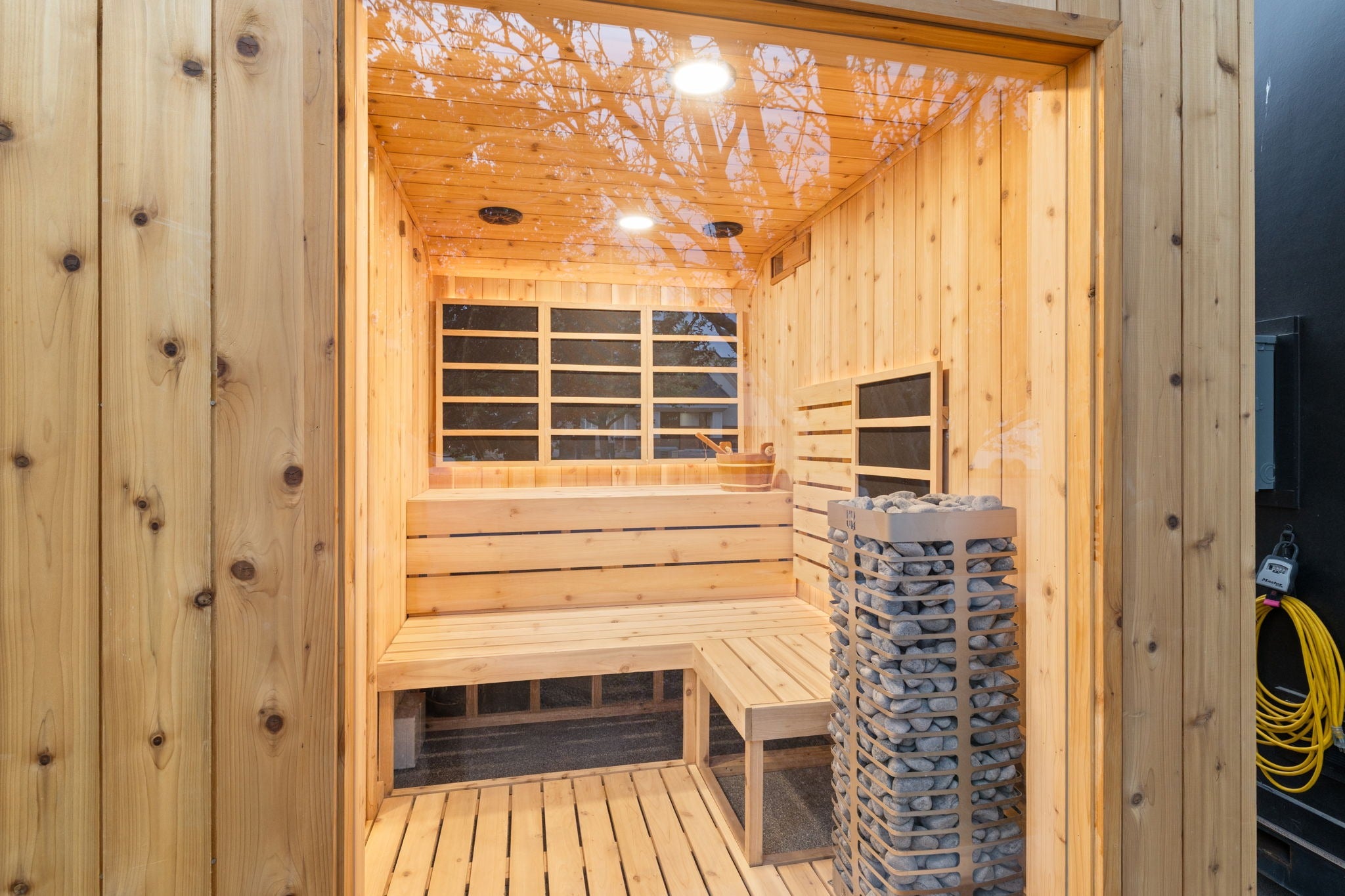 Sweaty Yeti 4-6 Person Outdoor Sauna & Cold Plunge Cabin in glass window with heater and wooden benches.