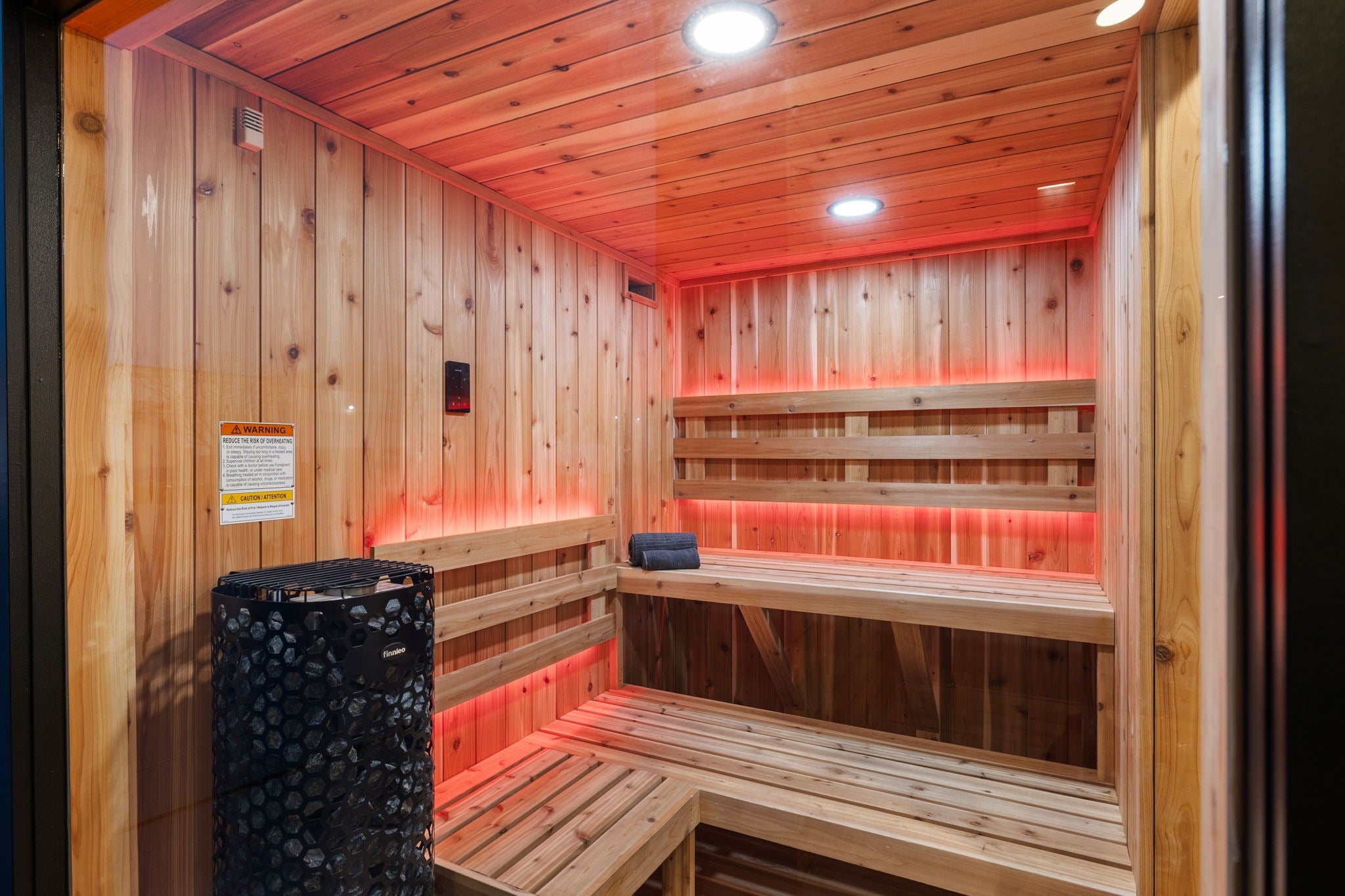 Wooden sauna with benches and a black cylindrical object inside