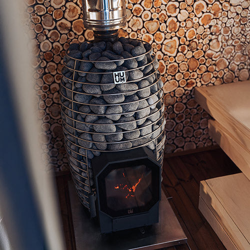 HUUM HIVE Flow Mini LS wood-burning stove installed beside sauna benches