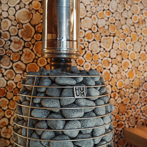 HUUM HIVE Flow Mini installed in a sauna with stones and chimney pipe